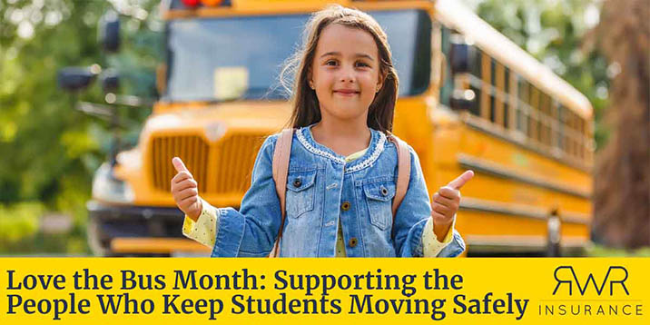 A young girl stands in front of a school bus